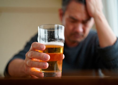 Мужчина сидит за столом Мужчина Держит стакан алкоголя